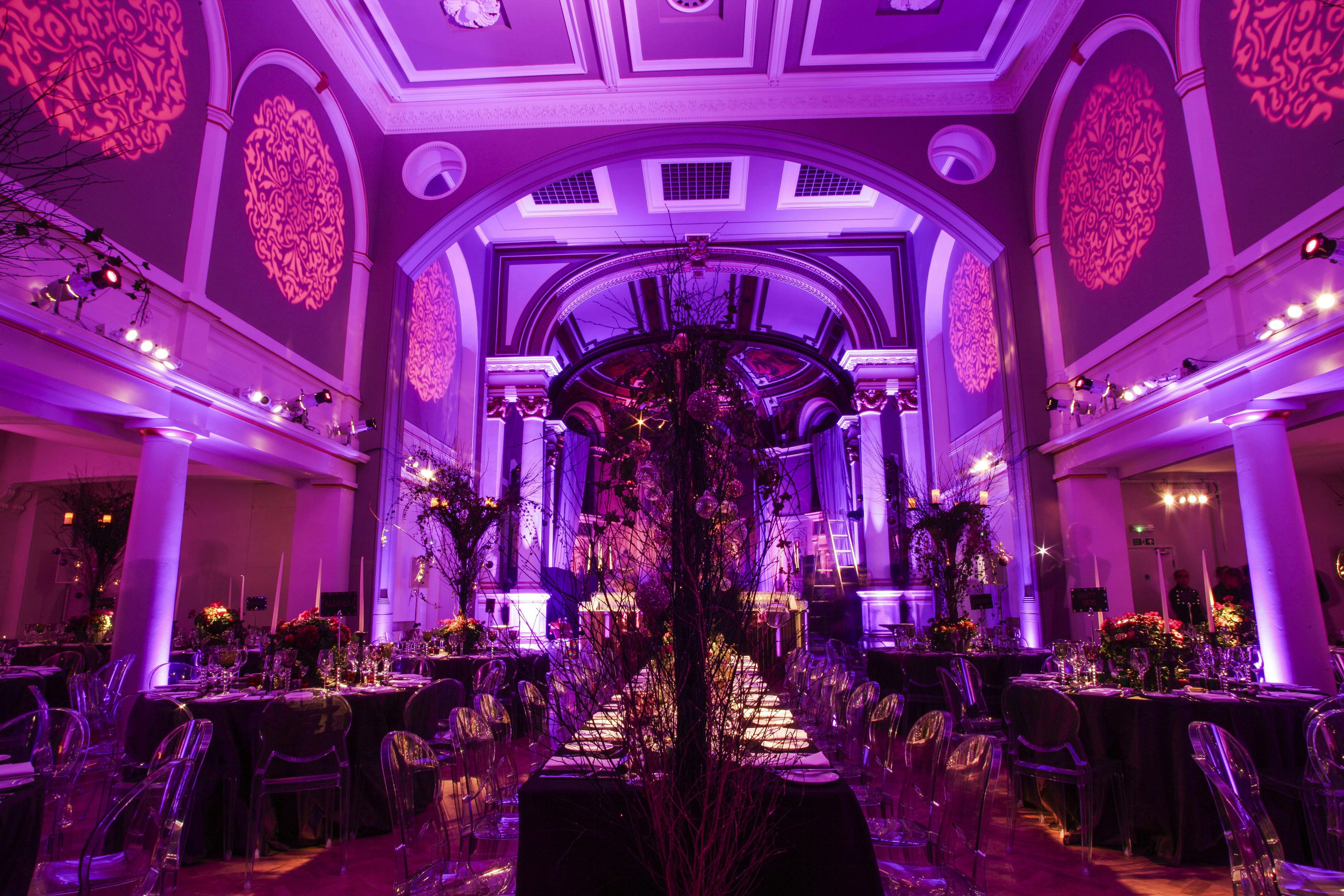 Elegant dinner setup in Soane Hall with purple lighting and floral arrangements.