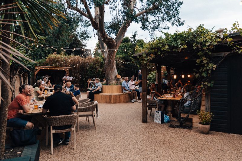 Vibrant outdoor event space with cozy seating and stage at The Lord Nelson Garden.
