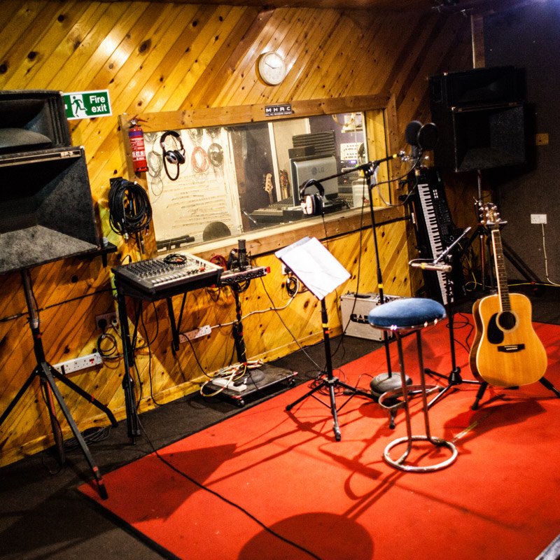 Cozy recording studio with microphone and guitar, perfect for music workshops and events.