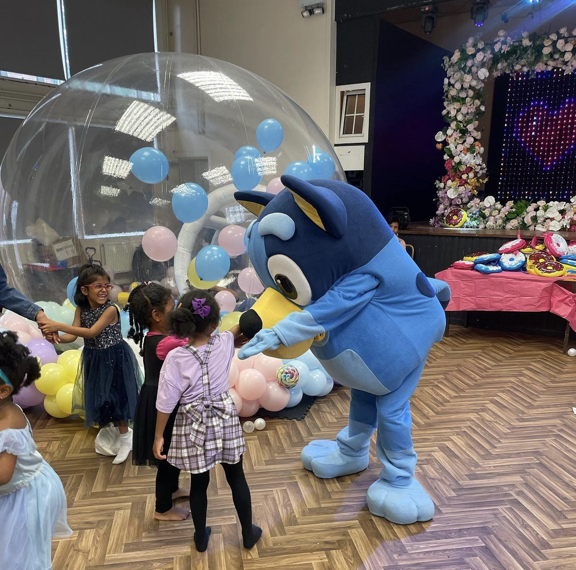 Costumed character entertains children in vibrant Magdalen Hall event space for parties.