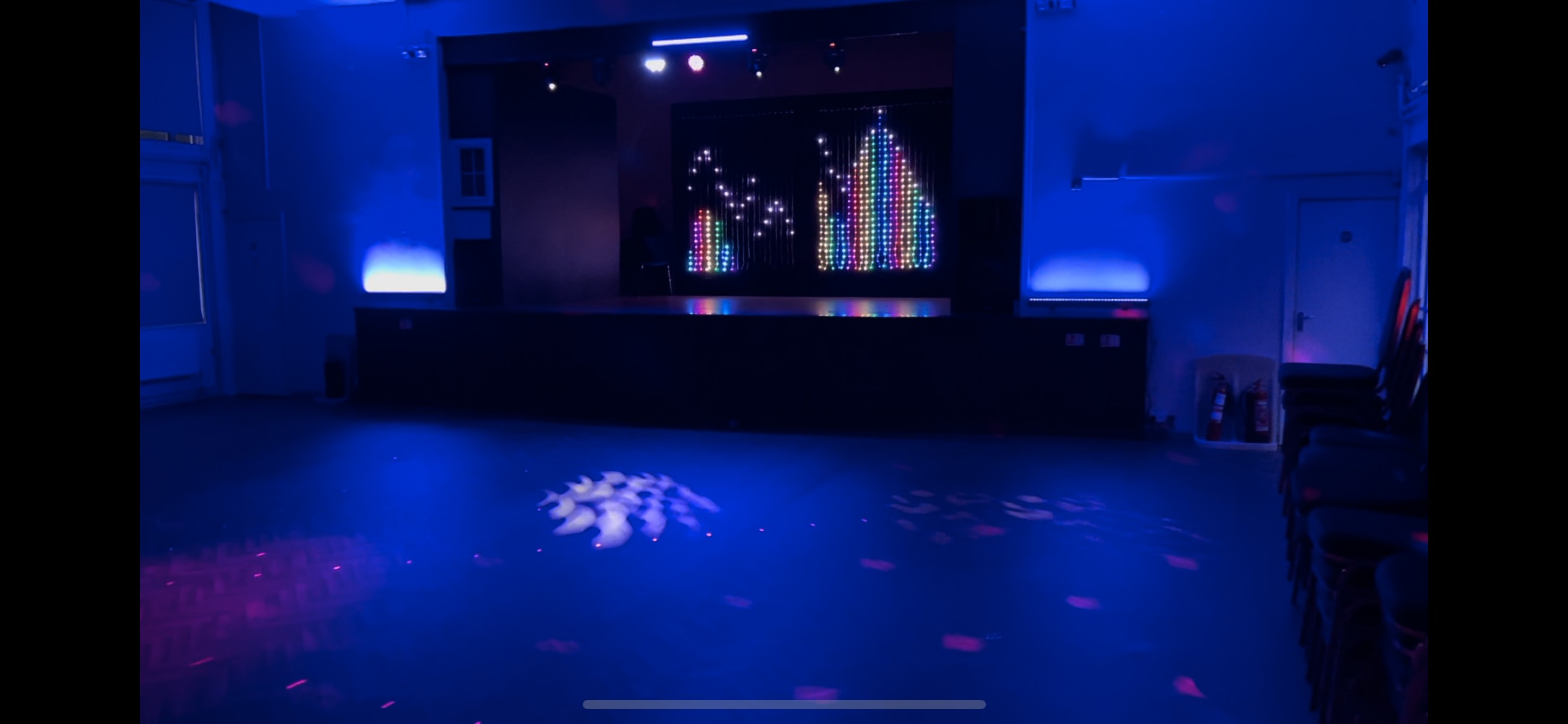 Main Hall at Magdalen Hall: vibrant LED-lit stage for events and gatherings.