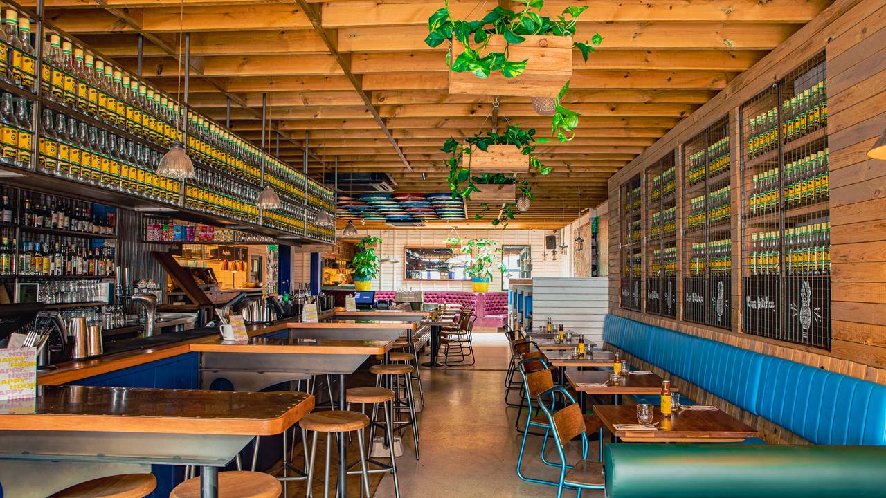 Vibrant cocktail bar with greenery, ideal for casual meetings and team-building events.