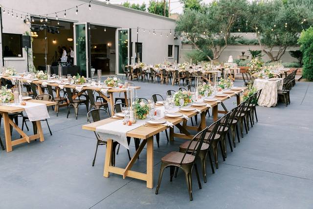 Outdoor event space with wooden tables and floral centerpieces, perfect for gatherings.