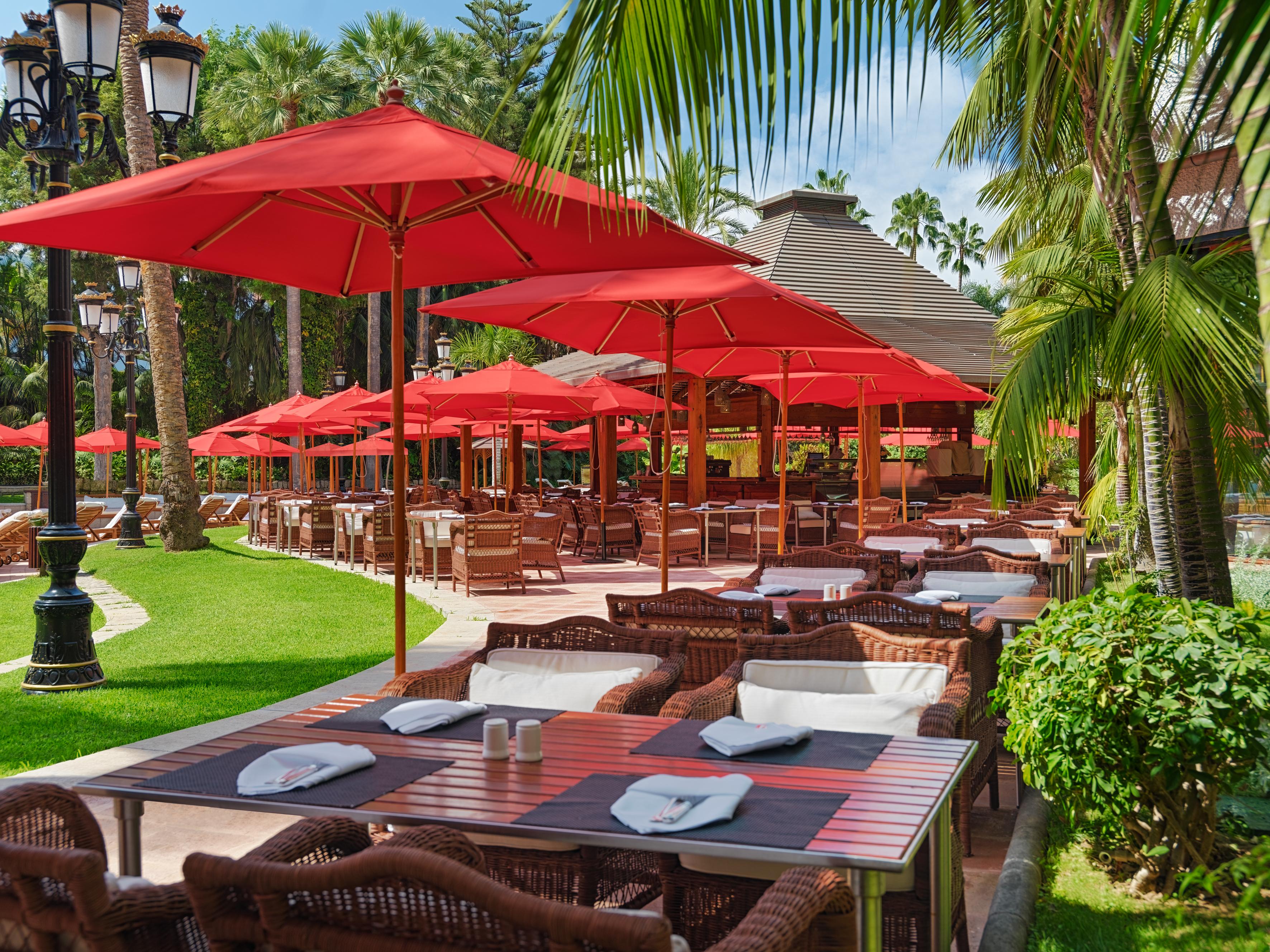 Outdoor dining at The Oriental Restaurant with red umbrellas, ideal for events and meetings.