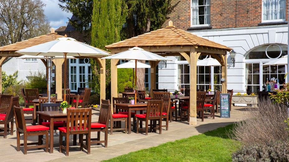 Outdoor event space at West Lodge Park Hotel with wooden gazebos and dining tables.