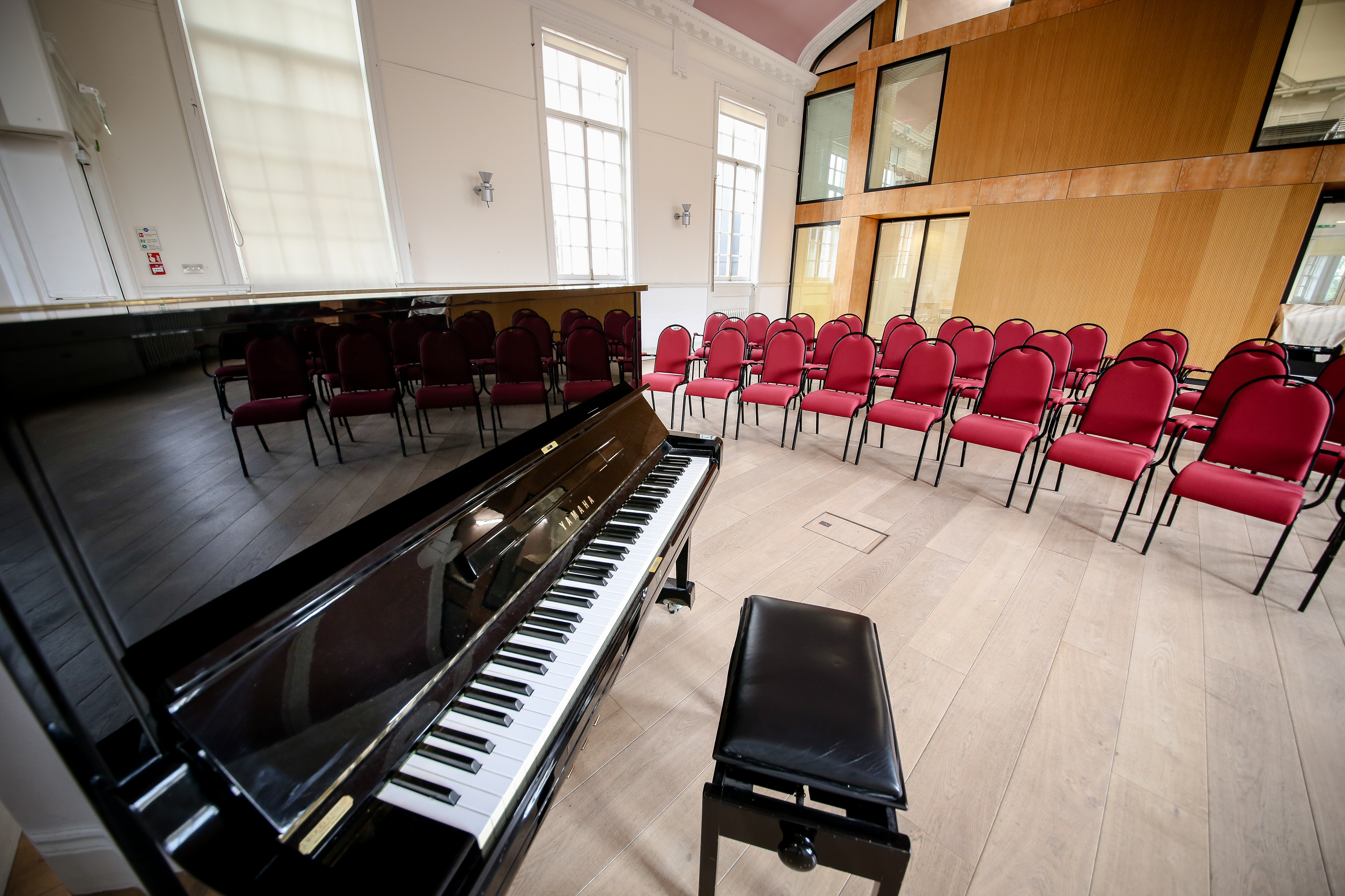 Event space in Nicolson Square, Edinburgh with grand piano and red chairs for performances.