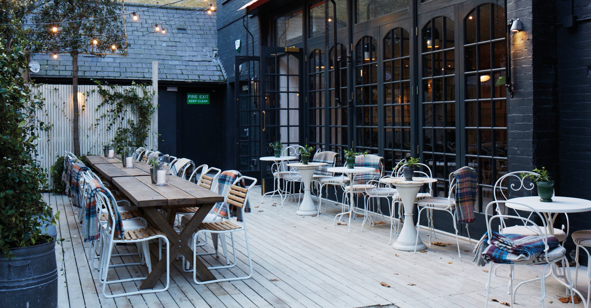 Charming outdoor private dining room with wooden table, ideal for events and gatherings.