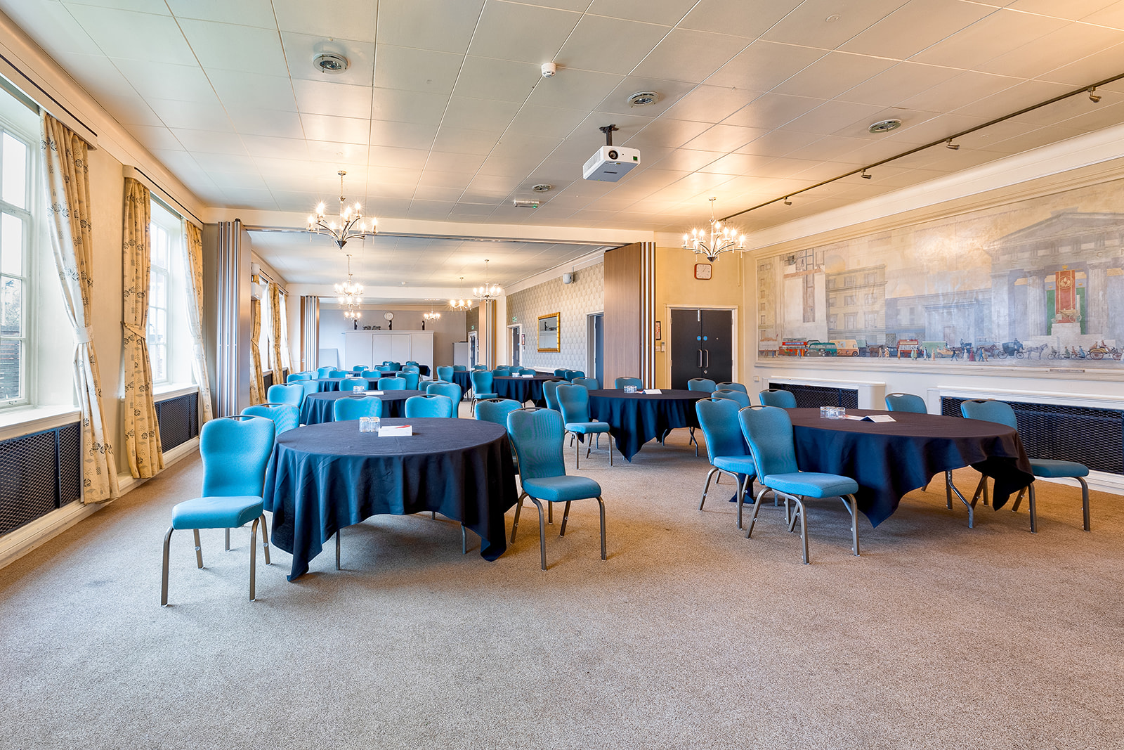 Spacious meeting room with round tables and blue chairs at Derby Conference Centre.