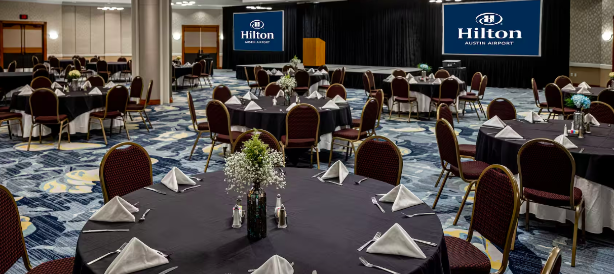 Elegant event space at Hilton Austin Airport with round tables, ideal for corporate meetings.