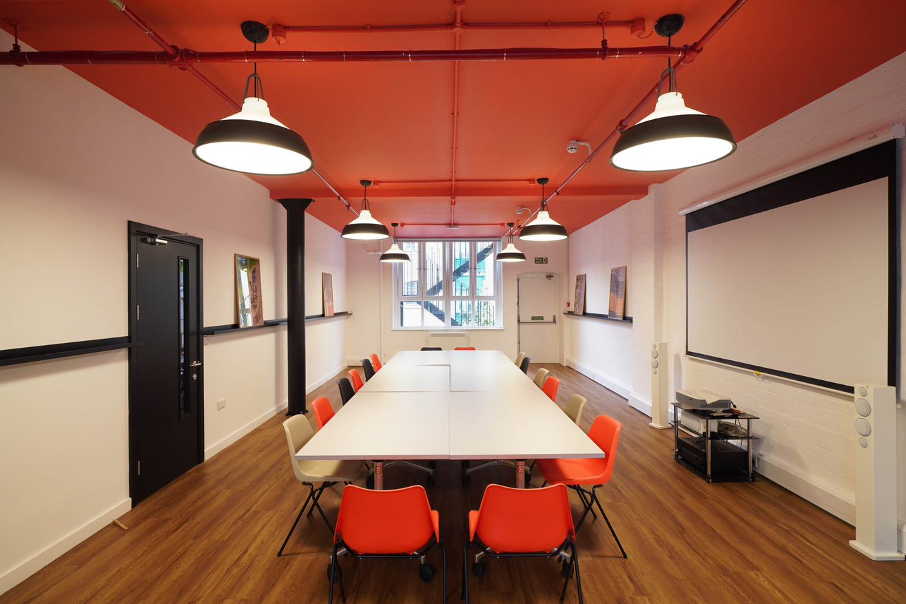 Modern meeting room in London Bridge Hive with orange chairs, ideal for workshops.