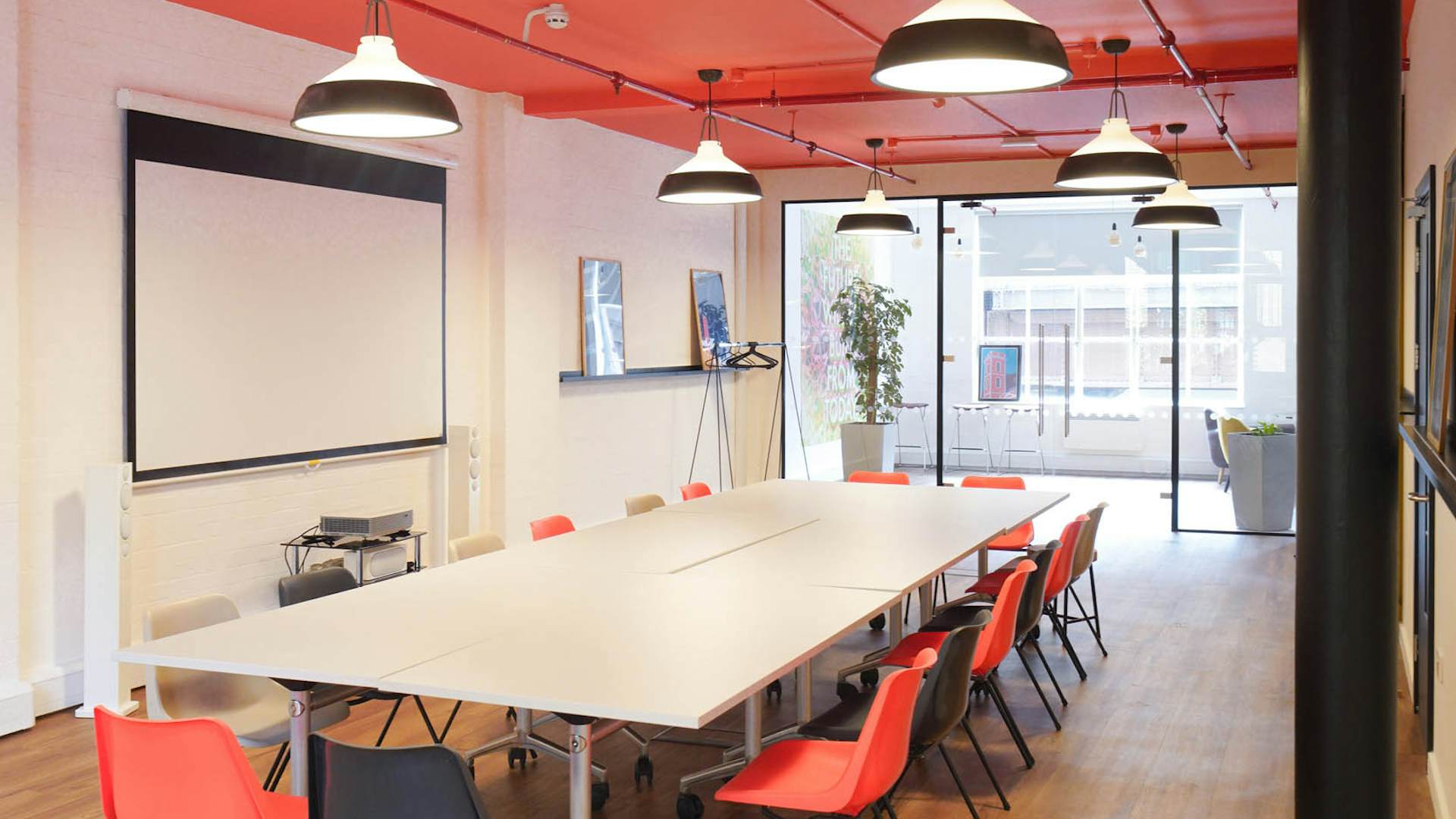 Modern meeting room in London Bridge Hive with colorful chairs and red ceiling.