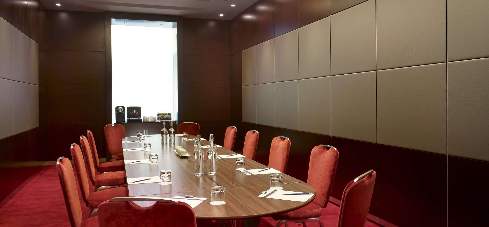 Modern meeting room at Salon Privé, featuring a long wooden table for corporate events.