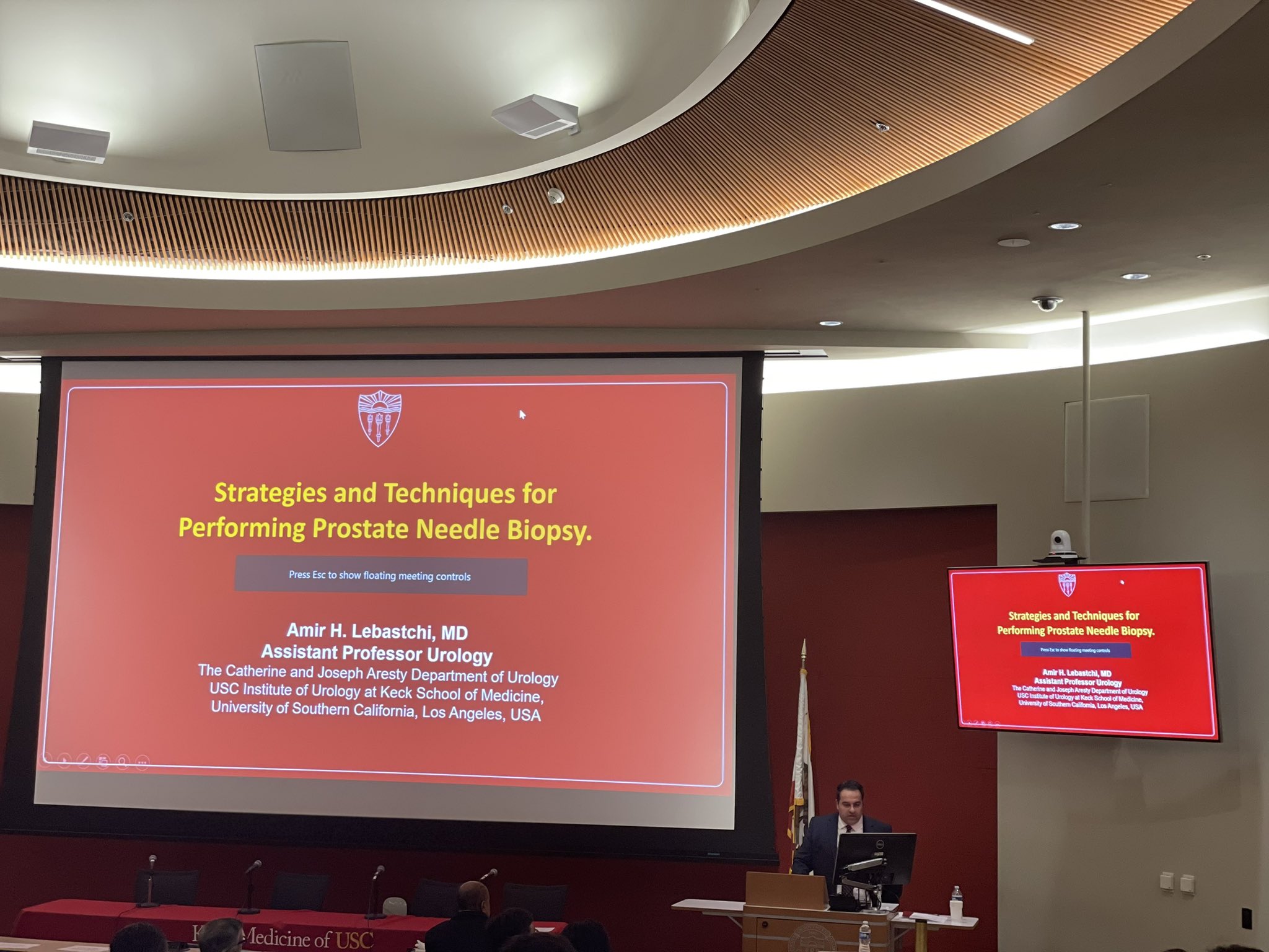 Catherine and Joseph Aresty Auditorium with speaker presenting medical talk on prostate biopsy.