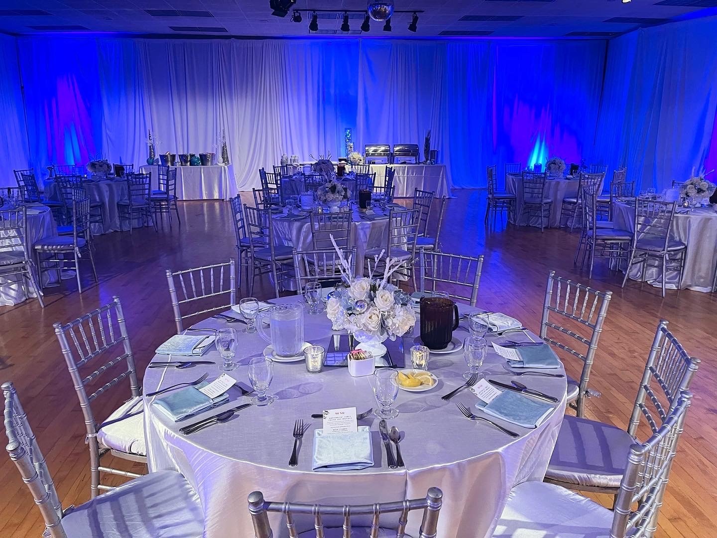 Elegant event space at Clark Street Terrace with silver tablecloths and blue lighting.