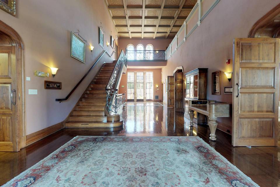 Elegant foyer with wooden features and sweeping staircase, ideal for receptions and networking.