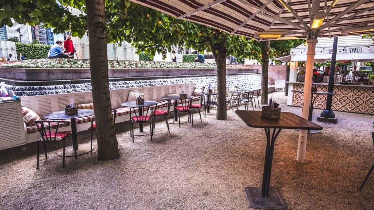 Outdoor event space with tables, serene water feature for networking and gatherings.