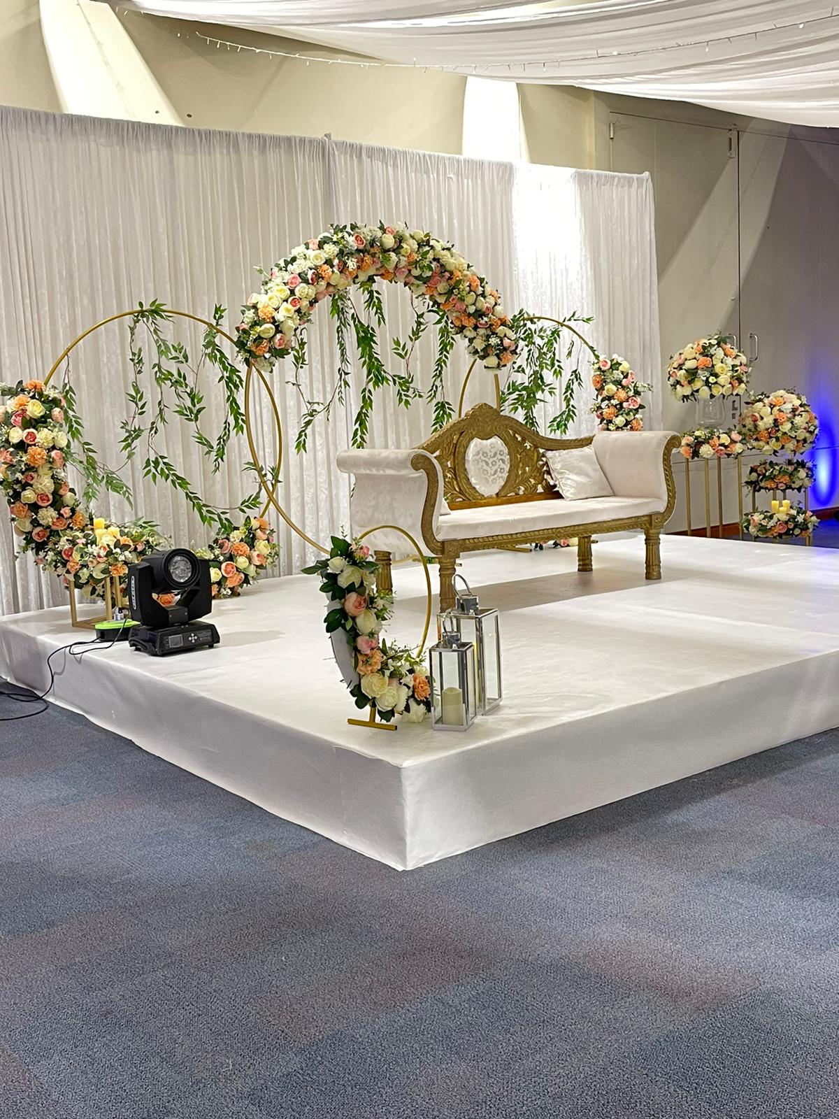 Elegant wedding mandap with white sofa and pastel floral arrangements.
