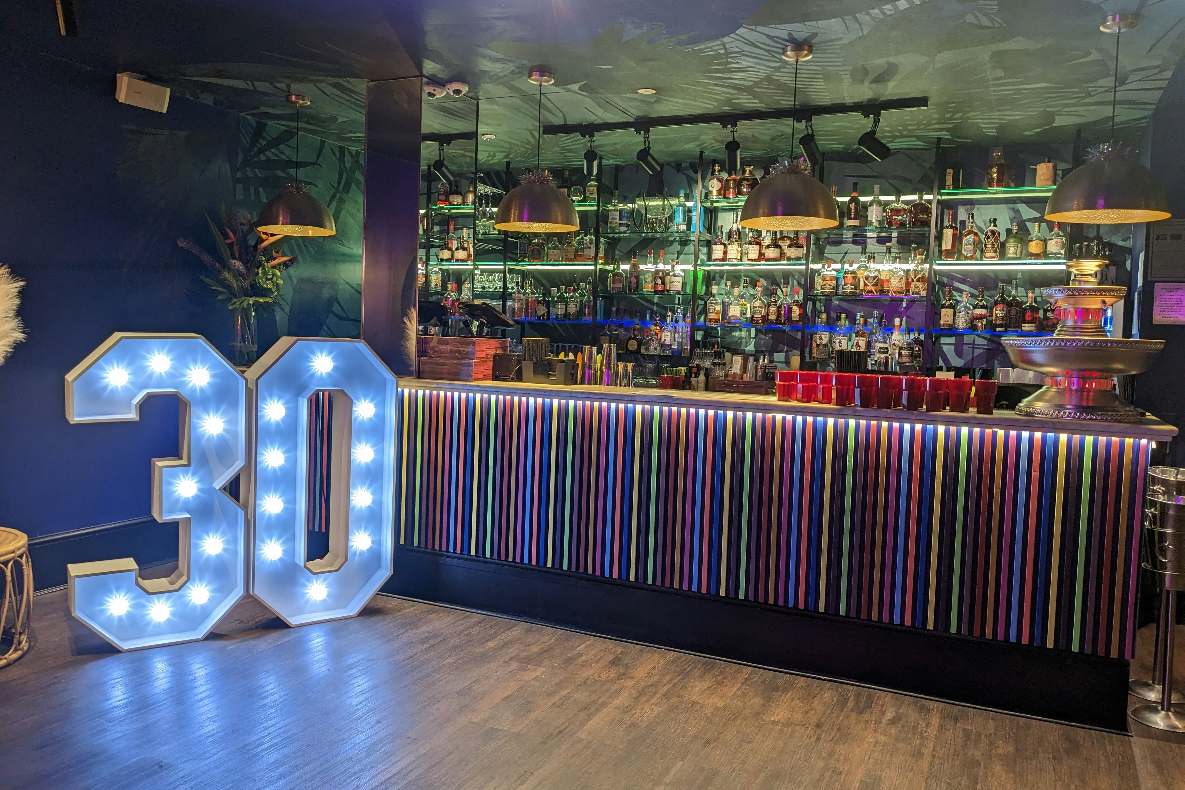 Vibrant bar at The Cottons Club with illuminated "30" sign for milestone celebrations.