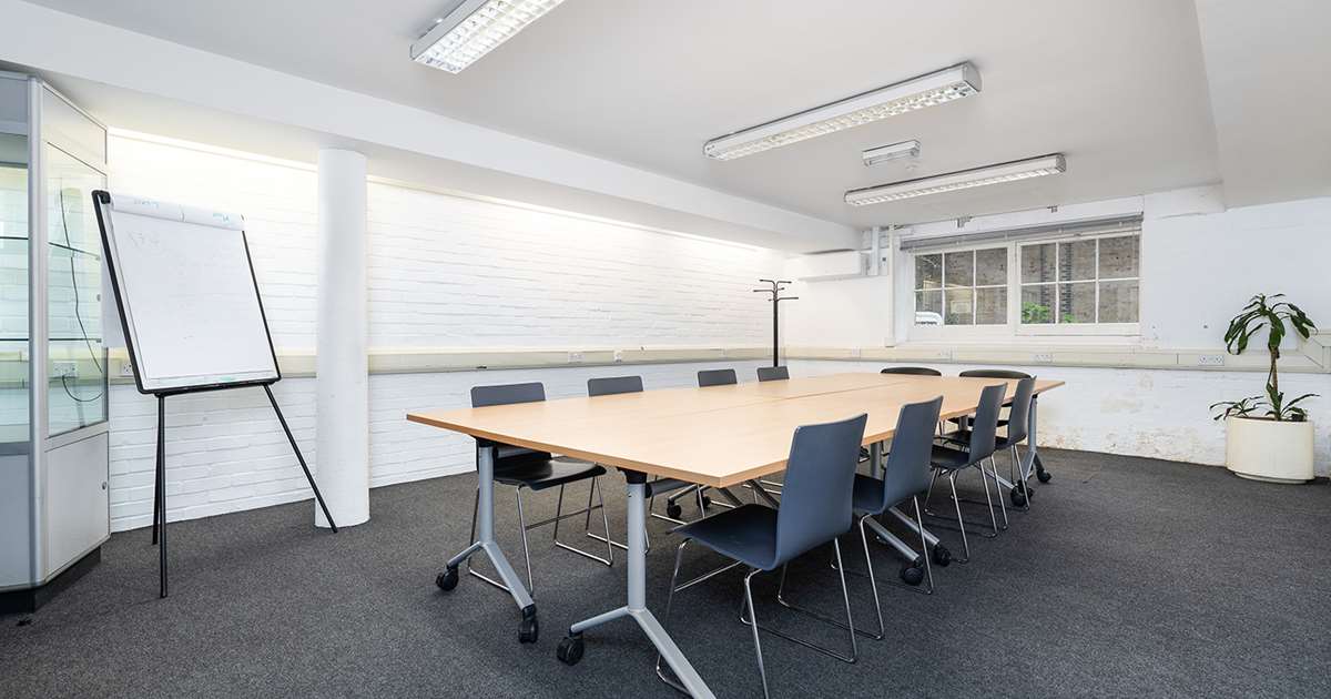 Modern minimalist meeting room with wooden table, ideal for workshops and strategic meetings.