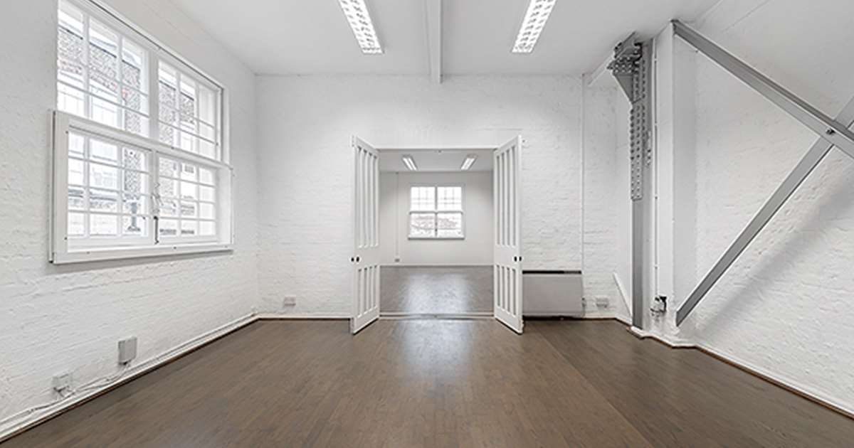 Bright minimalist meeting room with natural light, ideal for workshops and gatherings.