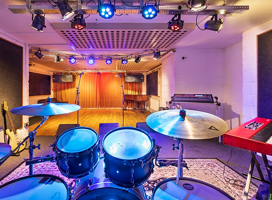 Versatile music rehearsal studio with drum set, ideal for concerts and events.