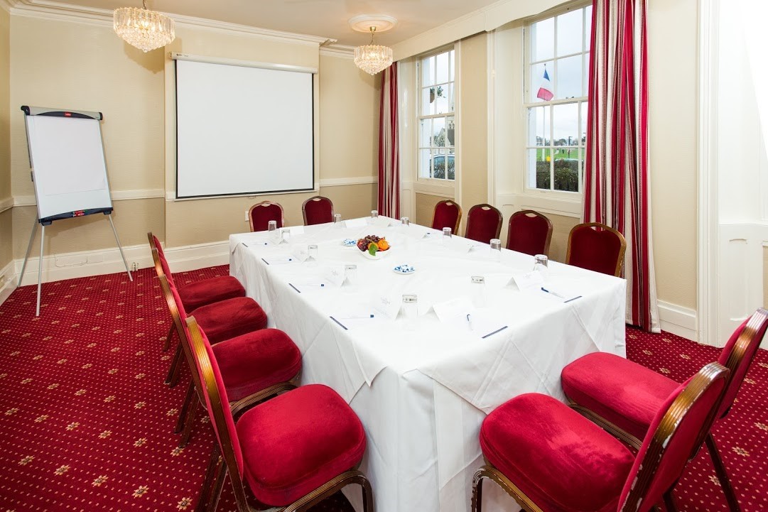 Conference room at The Clarendon Hotel with red chairs, ideal for corporate events.