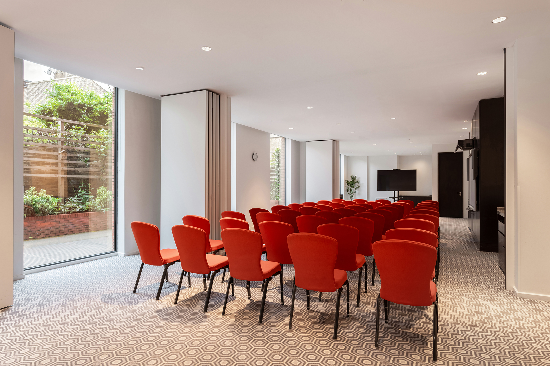 Modern meeting room with red chairs, ideal for corporate events and workshops.