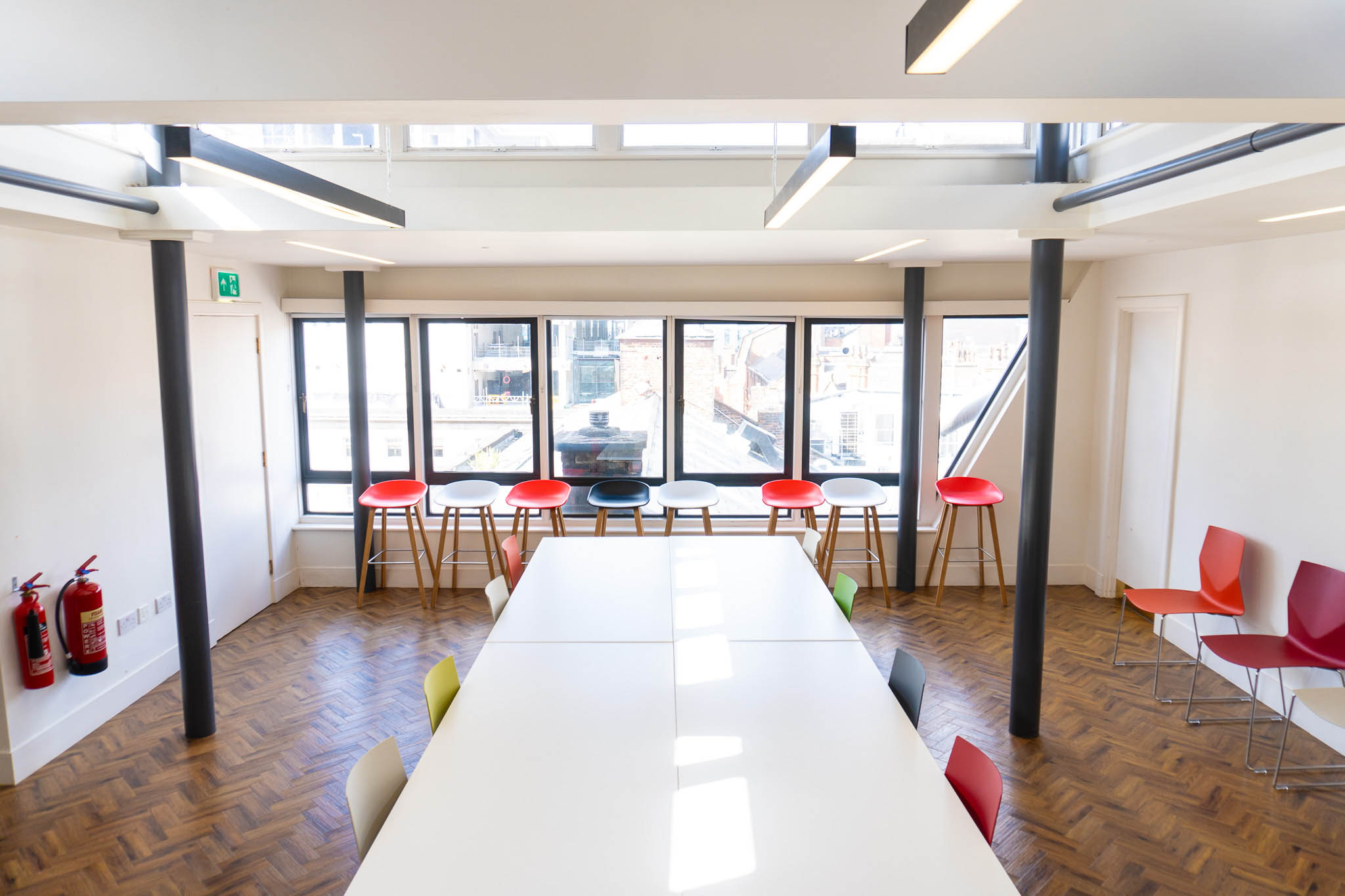Modern meeting room with large white table and colorful chairs in Barcelona office.
