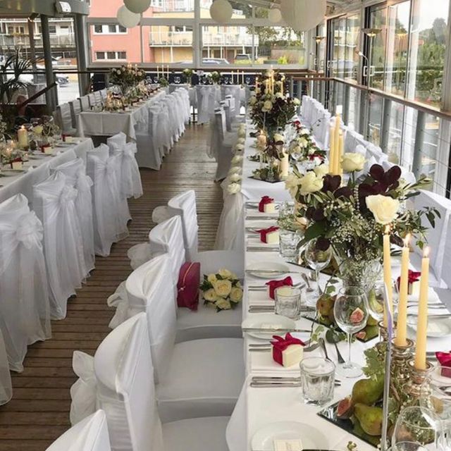 Glass-walled riverside dining room with elegant banquet setup for weddings and events.