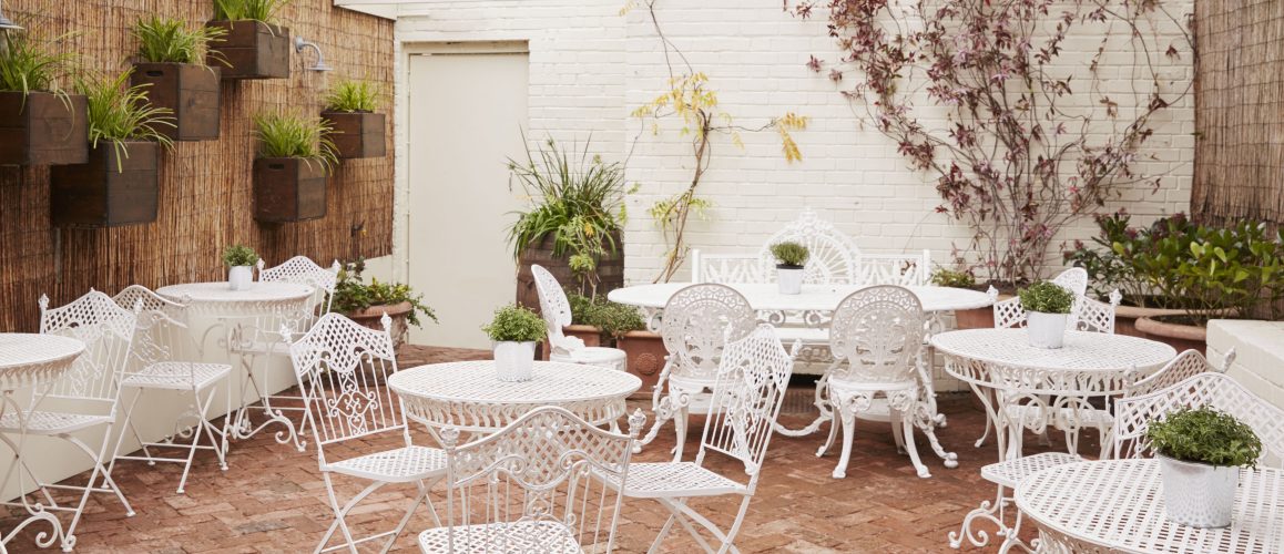 Charming beer garden with white wrought-iron furniture for events and gatherings.