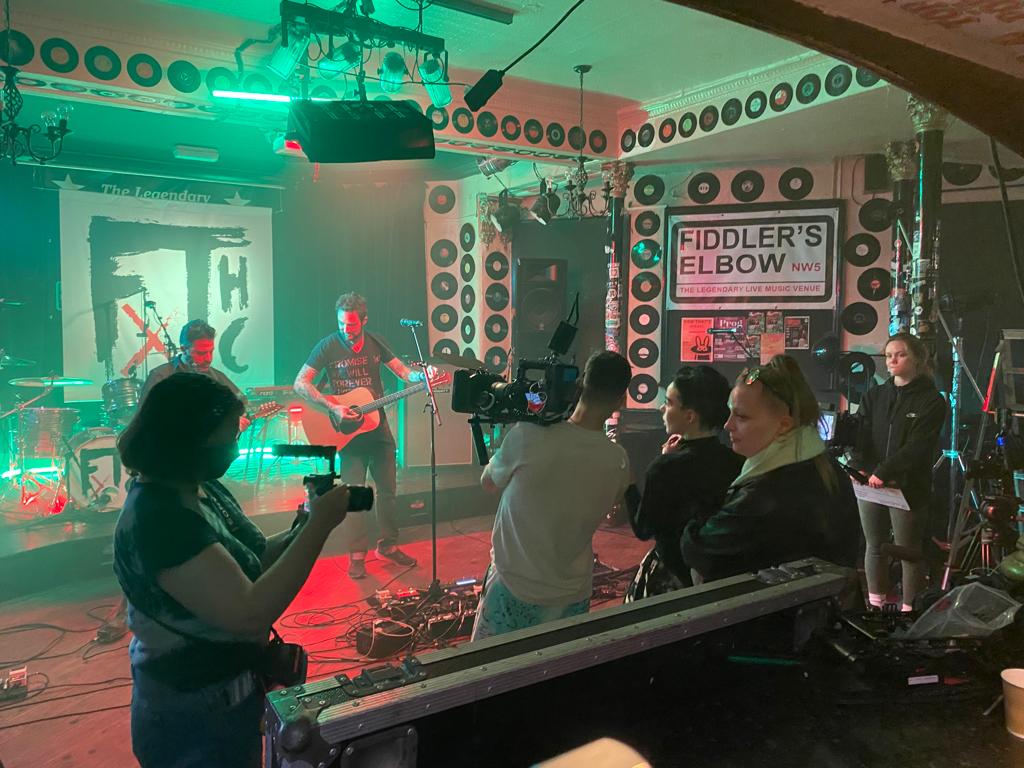 Live music event at The Fiddler's Elbow with vibrant stage lighting and engaged audience.