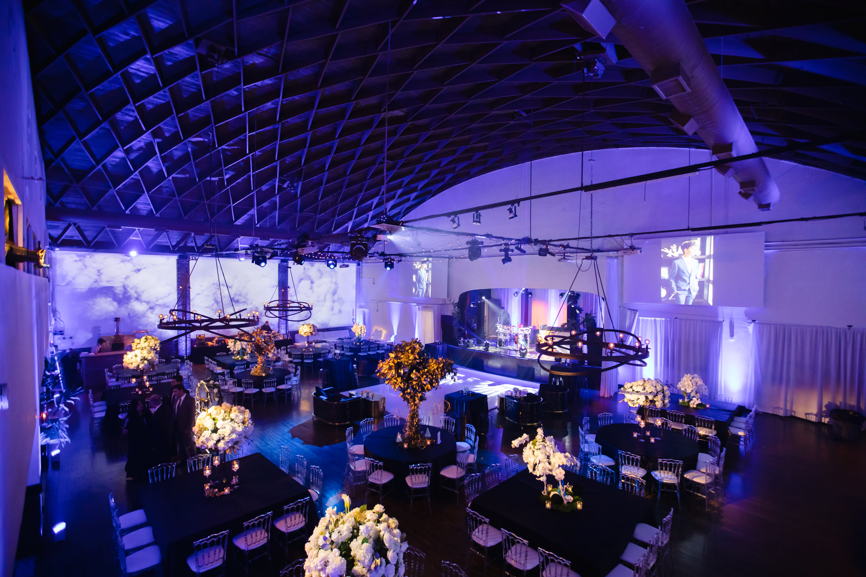 Elegant gala event space with dramatic lighting and luxurious floral arrangements.