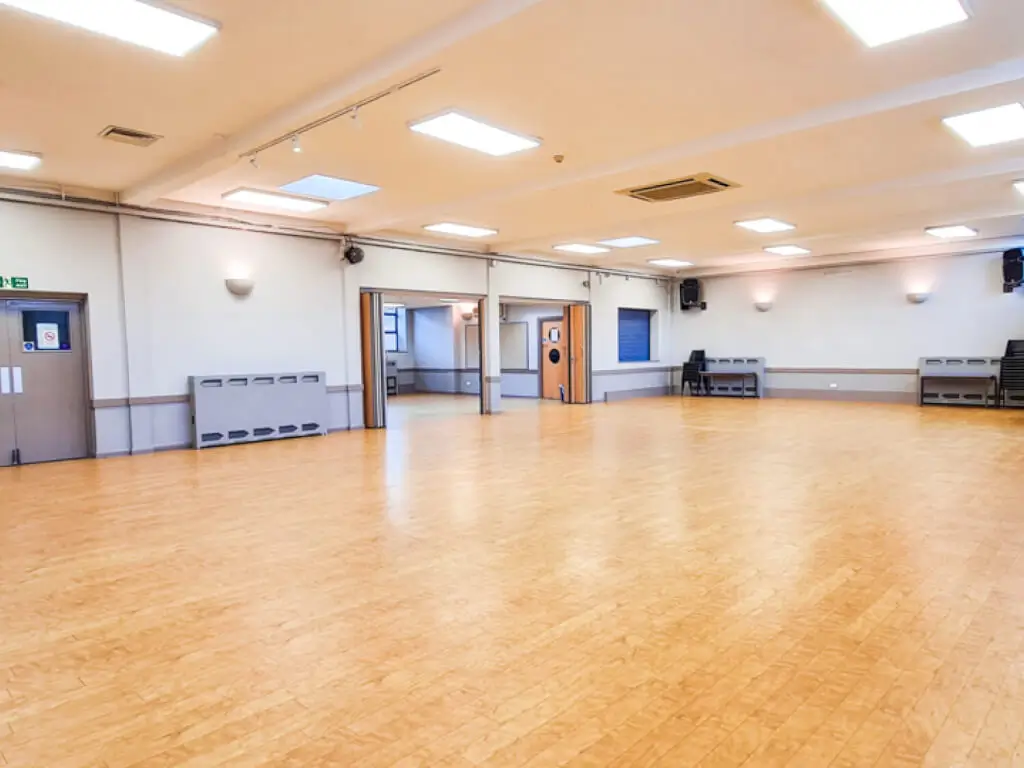 Spacious event space with polished wooden floor, ideal for gatherings and meetings.