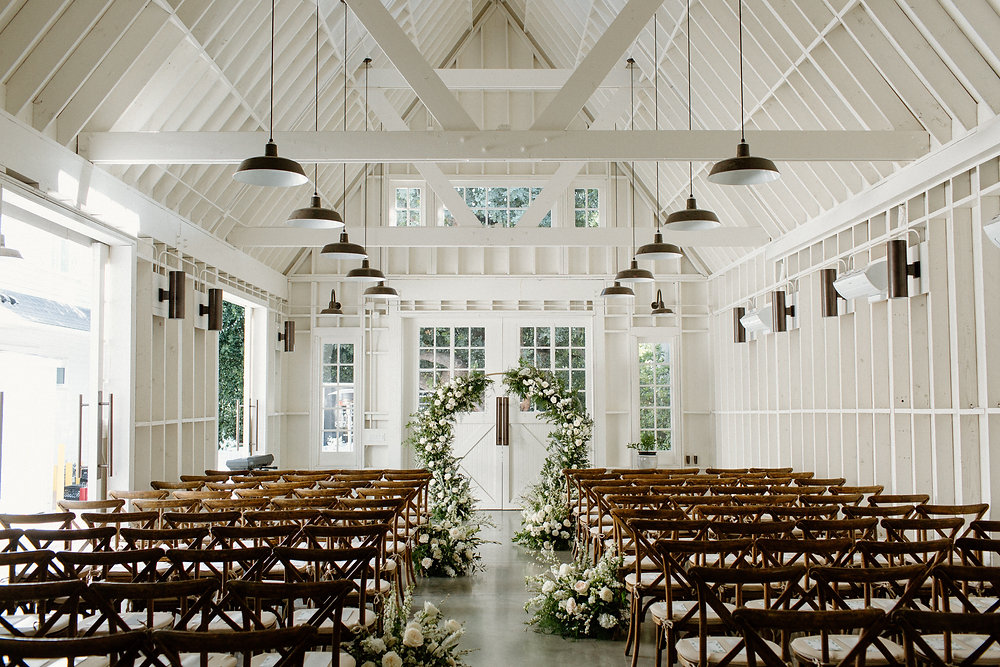 Elegant wedding barn venue with floral arch and natural light in Lombardi House.
