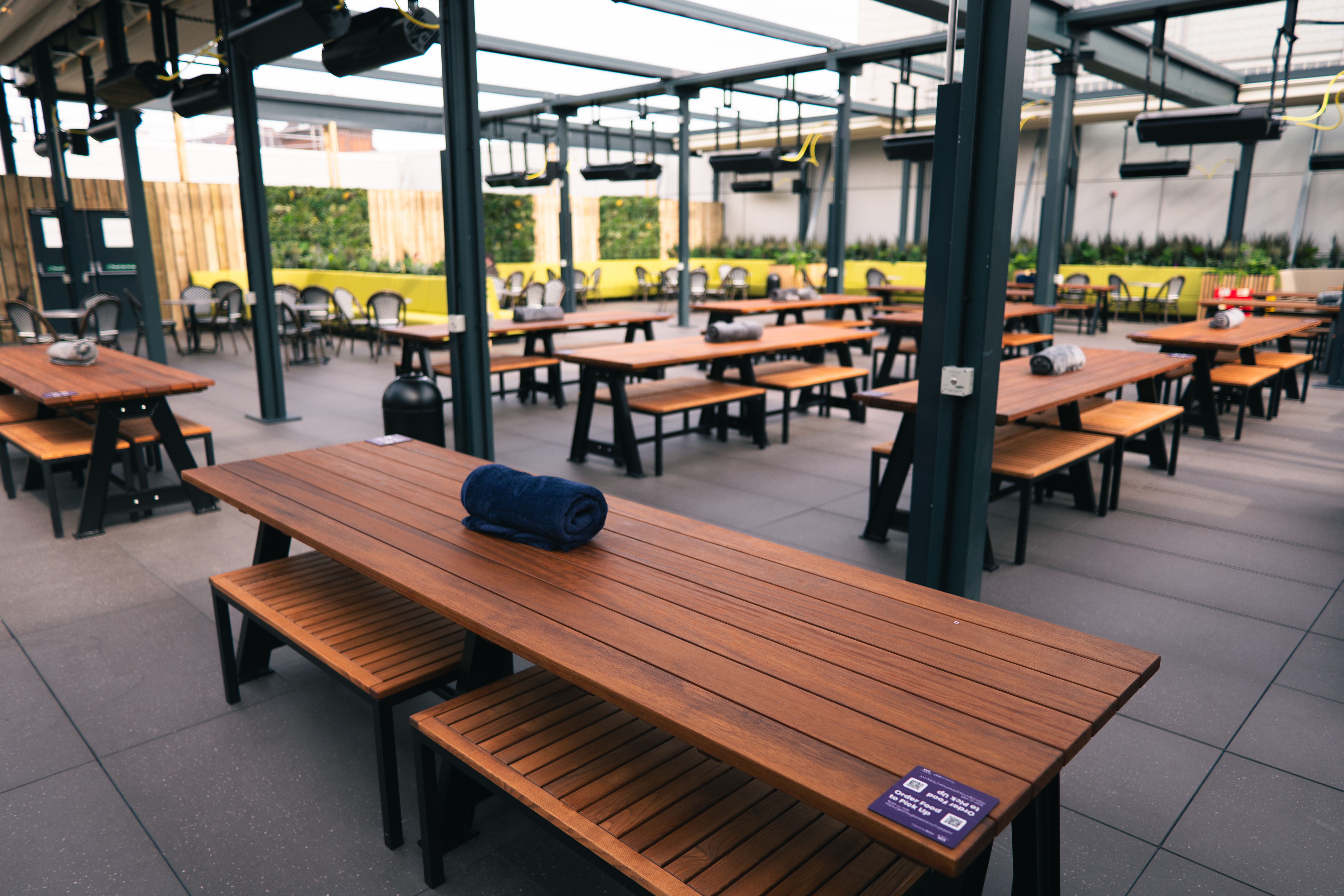 Spacious outdoor event venue with wooden tables for gatherings and celebrations.