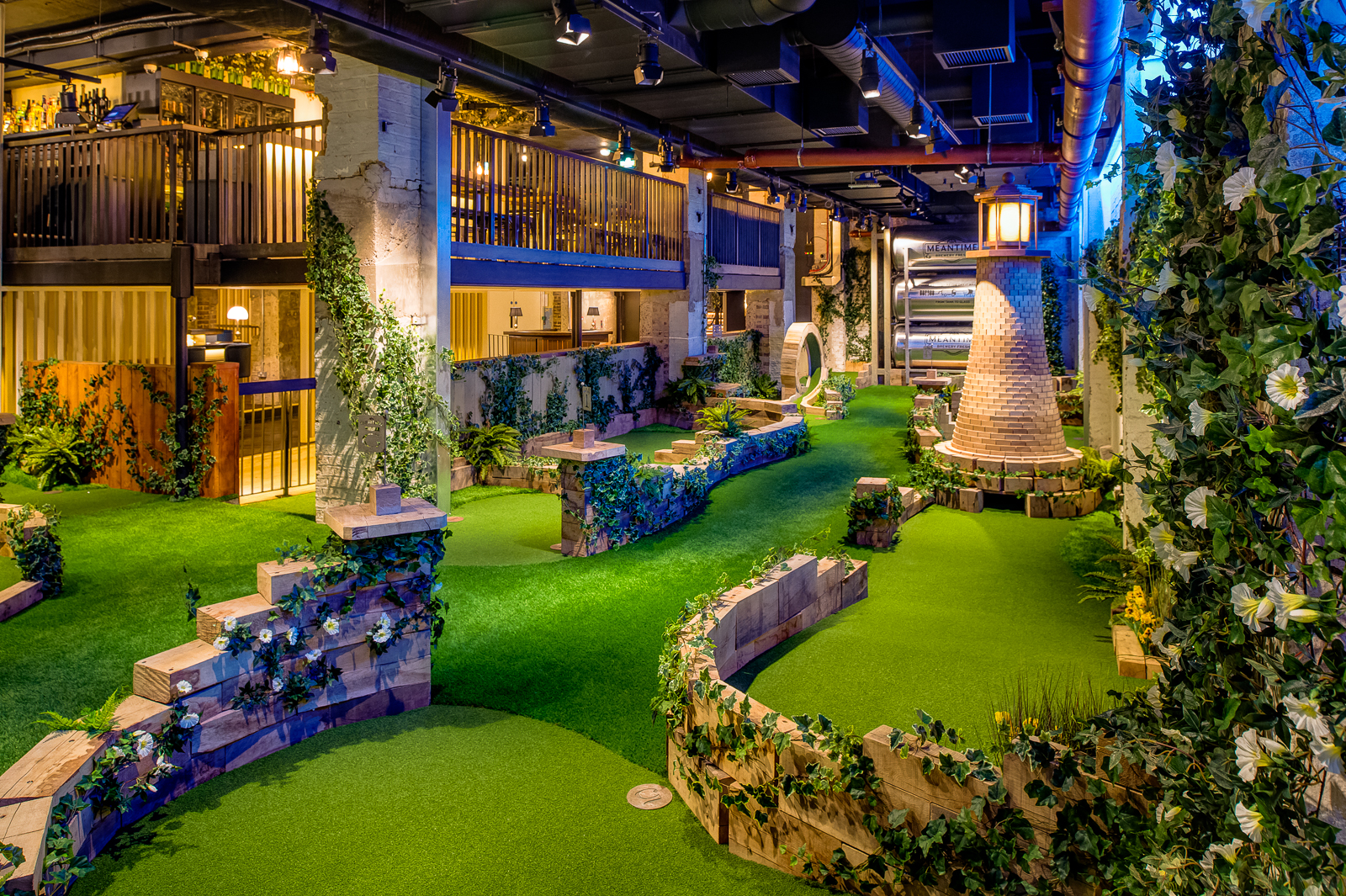 Indoor mini-golf venue with greenery for team-building events and gatherings.