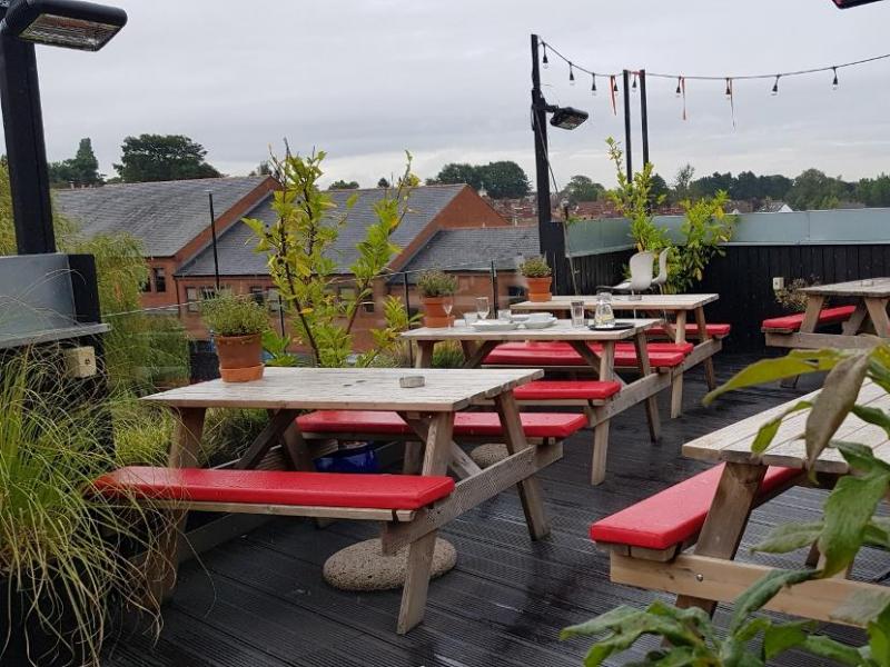 Rooftop pub venue with rustic tables, ideal for outdoor gatherings and networking events.