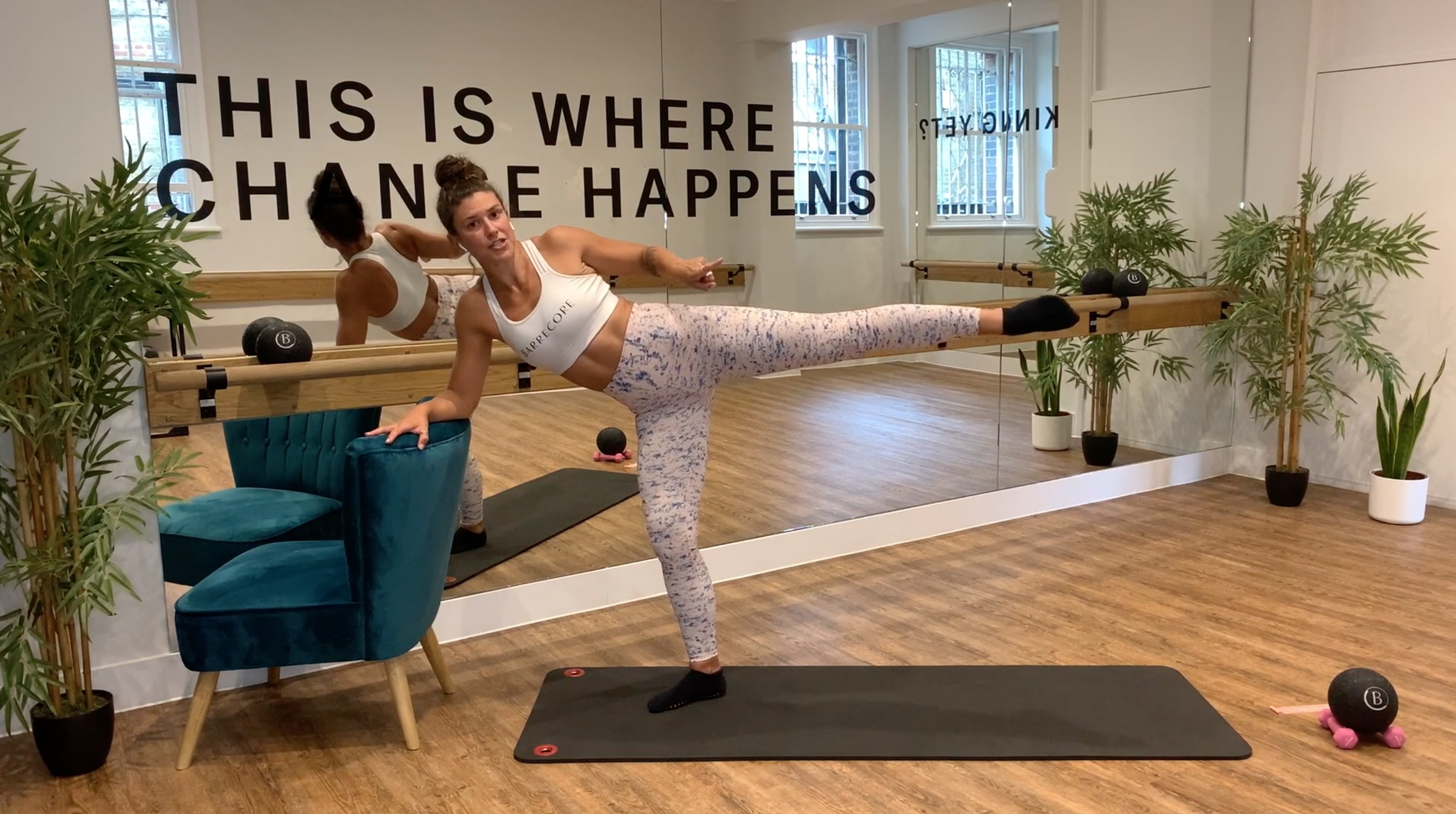 Fitness instructor demonstrating workout in bright Barrecore Chiswick studio for wellness events.