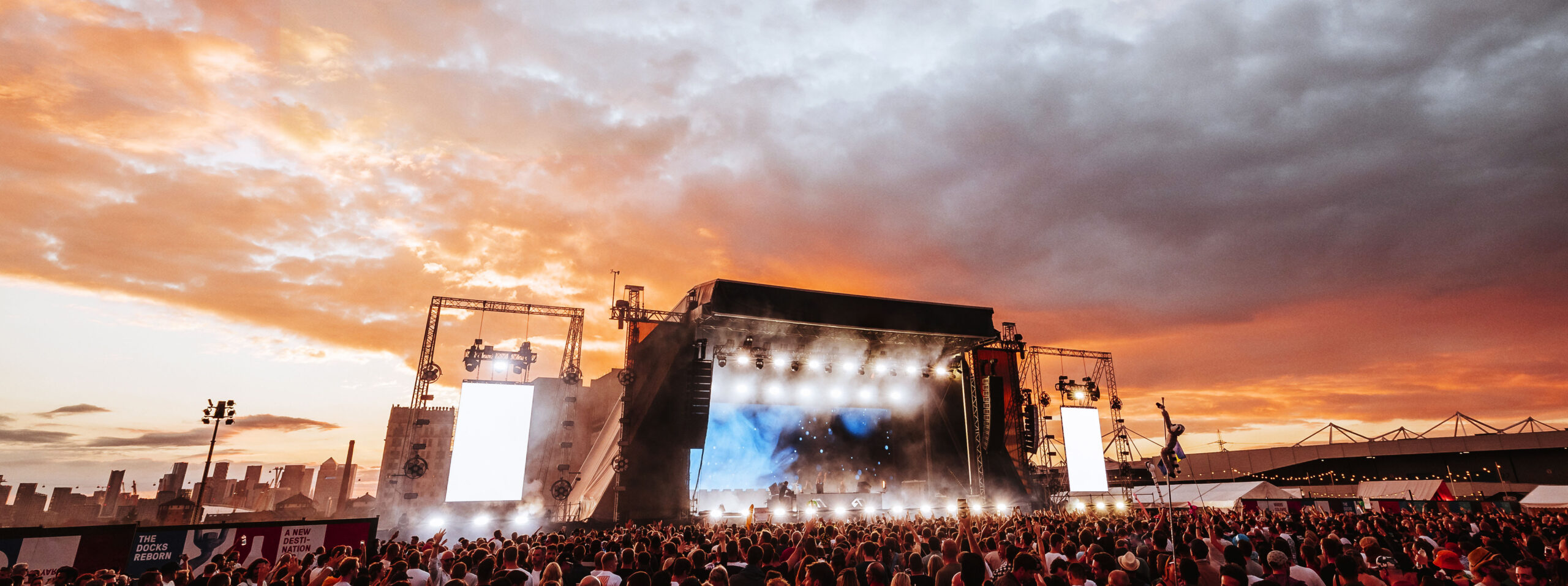 Vibrant outdoor concert at Silverworks Island with a stunning sunset backdrop.