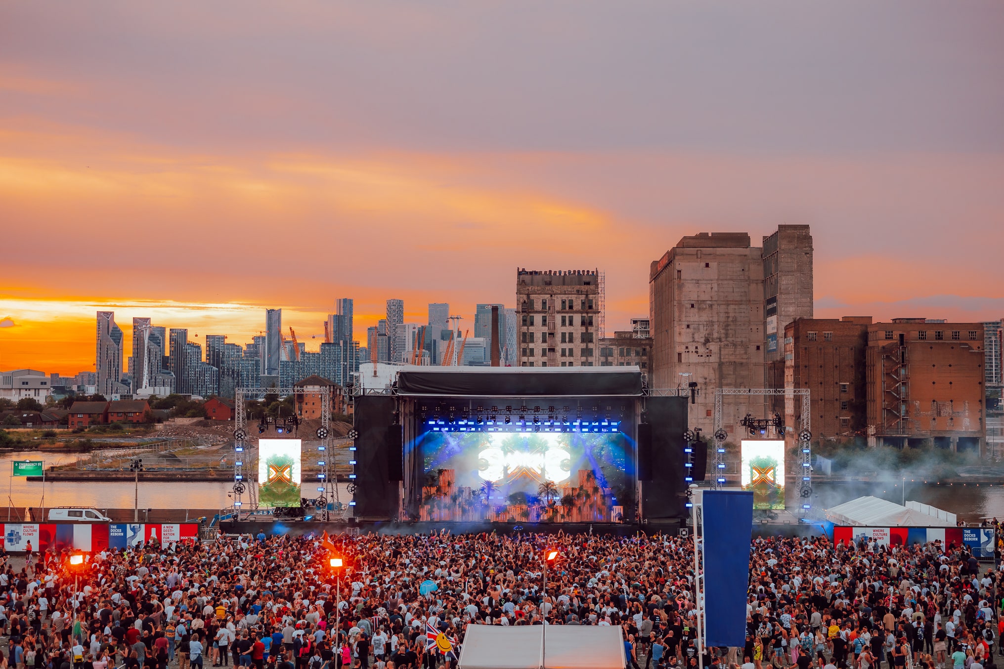 Vibrant outdoor concert at Silverworks Island with colorful lights and sunset backdrop.