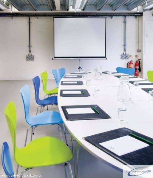 Modern meeting room with oval table, colorful chairs for creative collaboration.