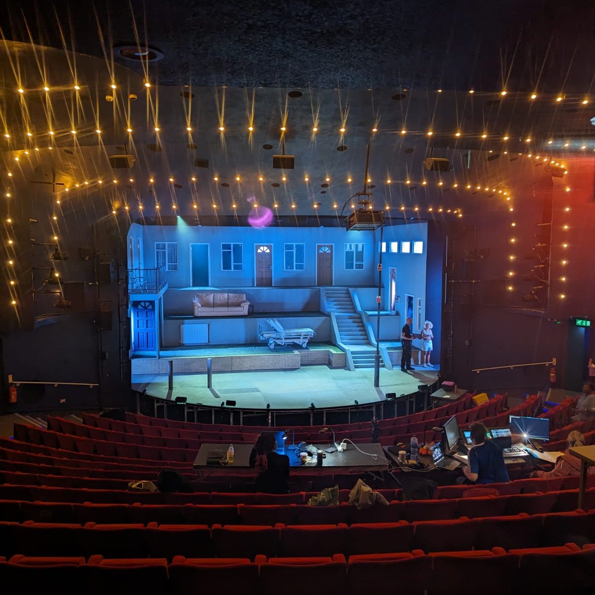 Theatre stage with warm lights and detailed backdrop for an intimate performance event.