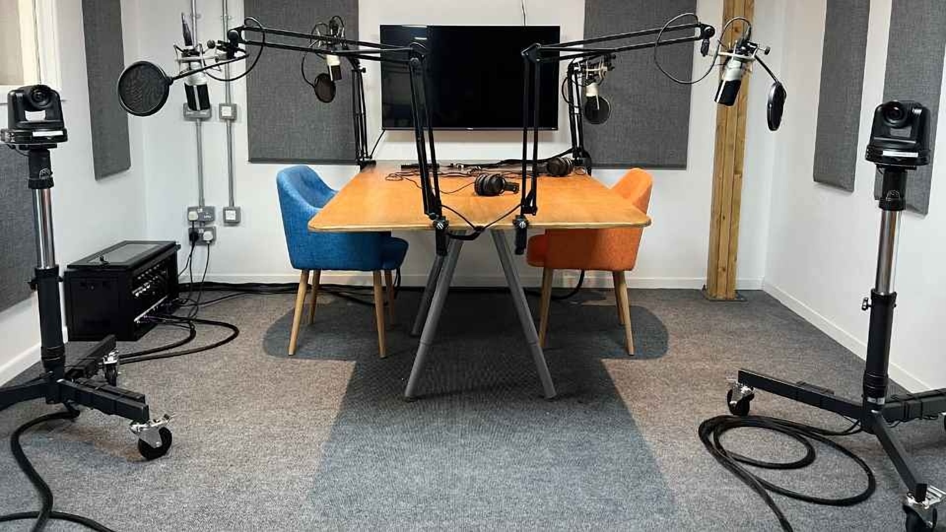 Modern podcast room with colorful chairs and soundproofing for interviews and discussions.