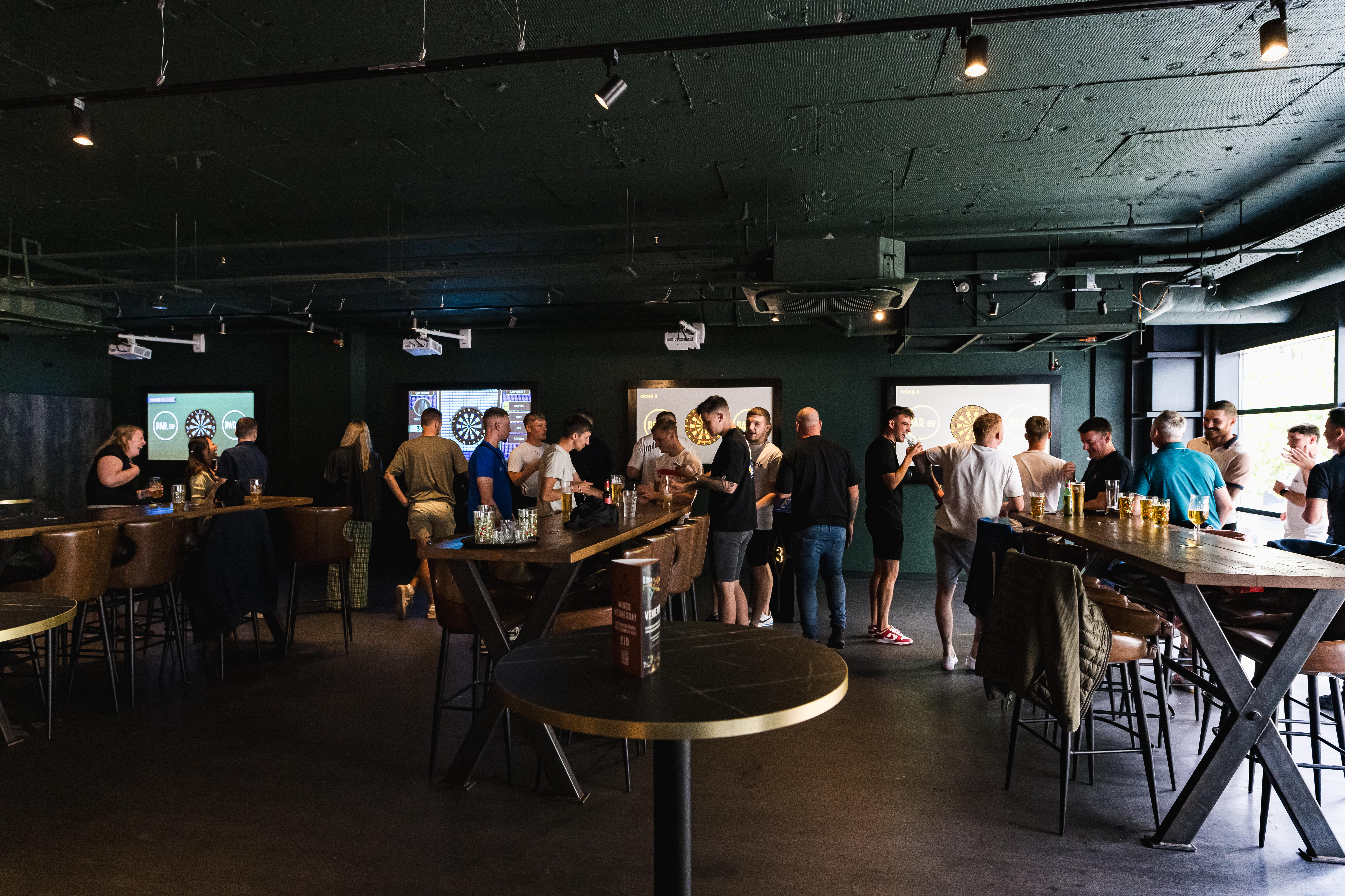 Vibrant networking event in Darts Area, Par 59 Bristol with high-top tables and screens.