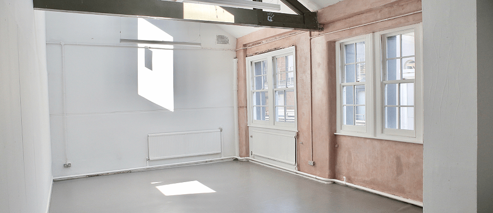 Bright minimalist event space with large windows, perfect for workshops and meetings.