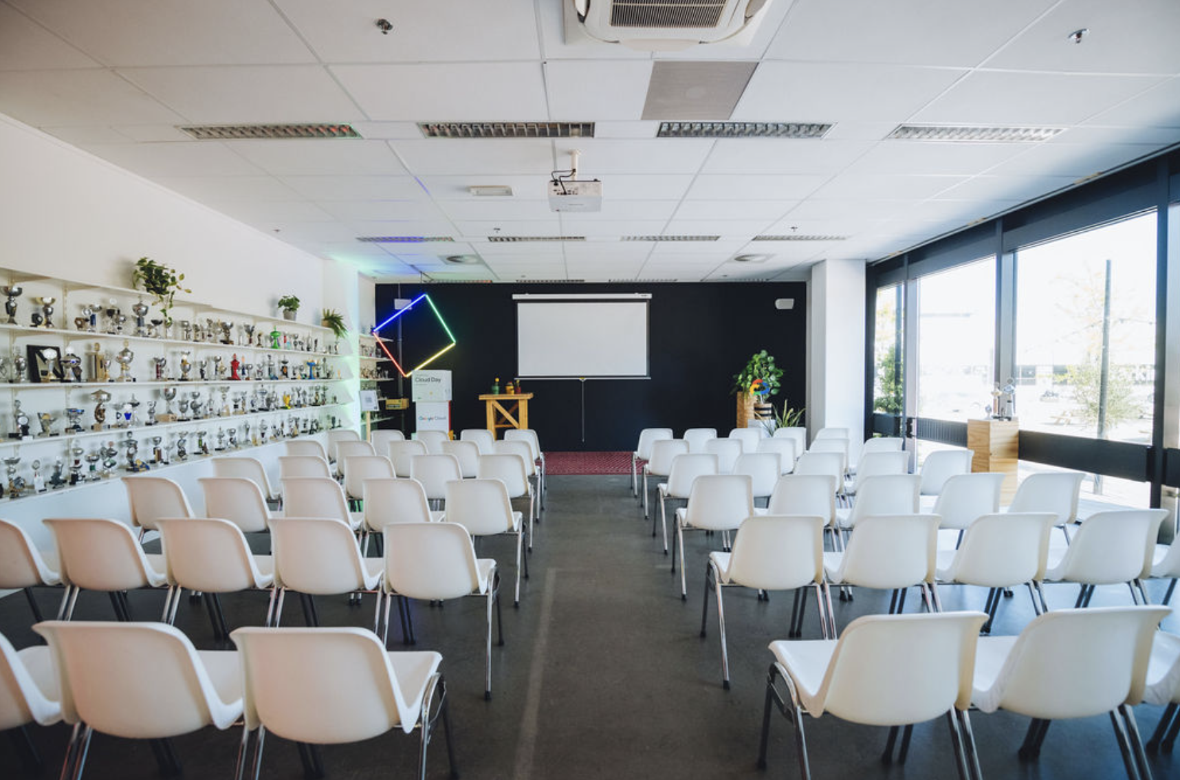 Meeting space at The Chris in B. Amsterdam with white chairs and projector screen for events.