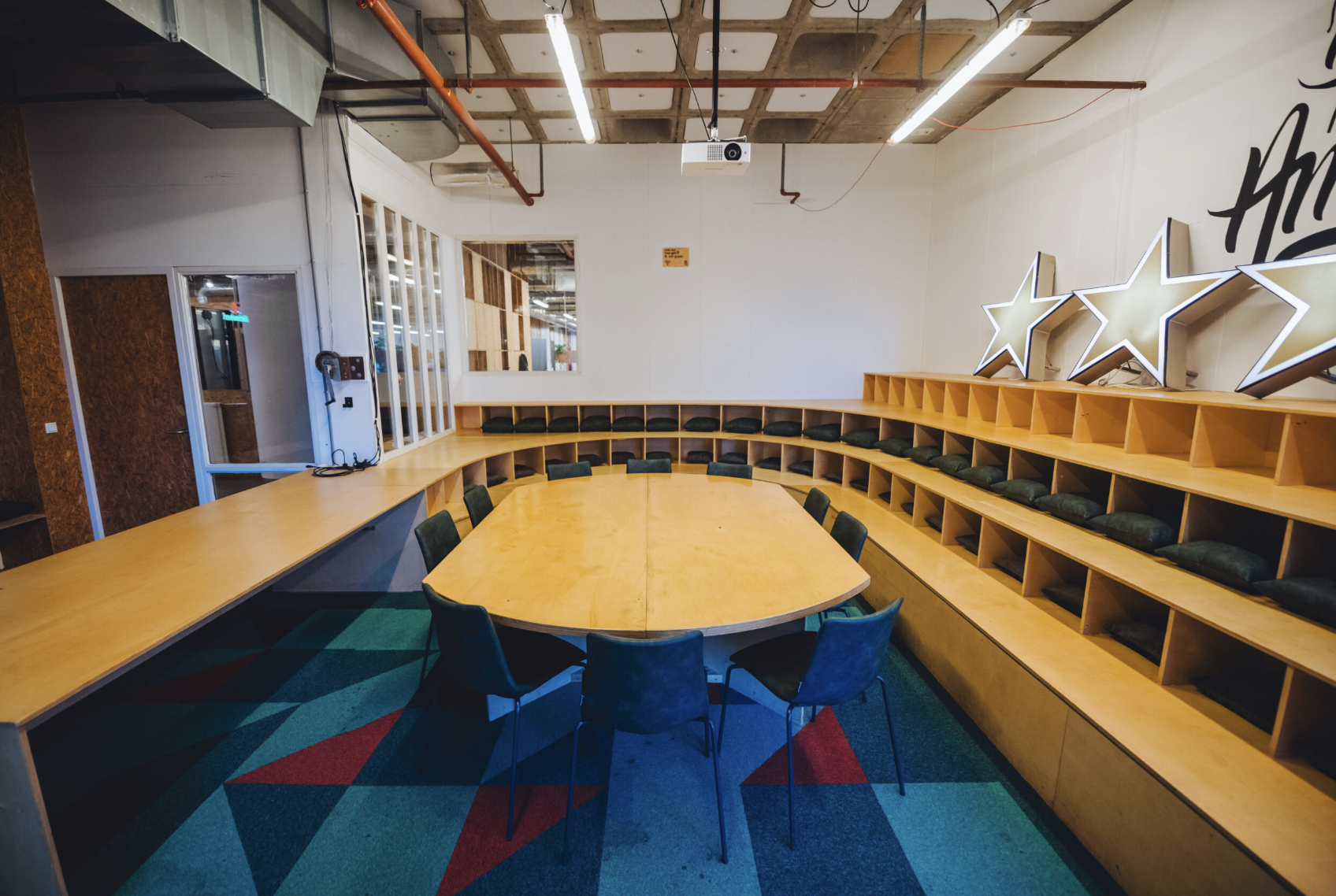 Modern meeting space with curved table, vibrant carpet for workshops and brainstorming.