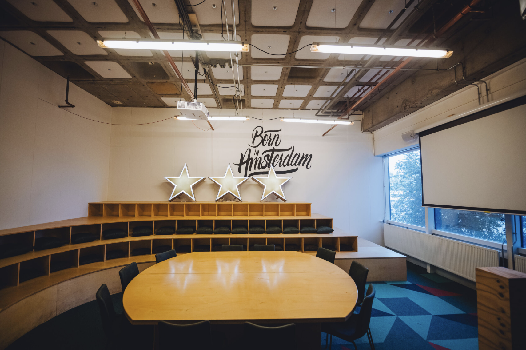 Modern meeting space in B. Amsterdam with round wooden table for collaboration.