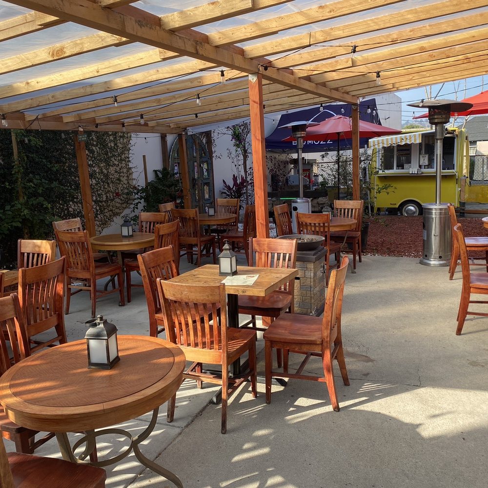 Charming covered patio with wooden tables, vibrant umbrellas for outdoor events in Bexx Secret Garden.