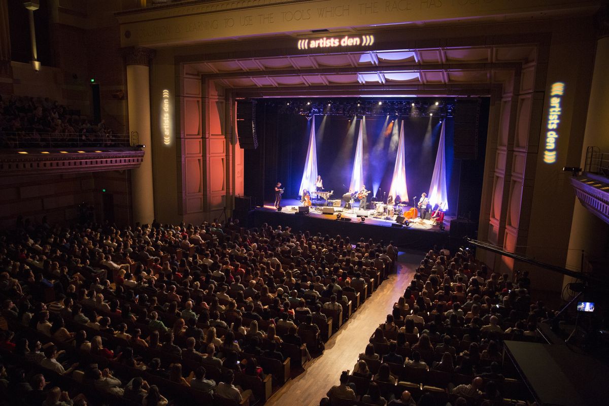 Packed Royce Hall stage with professional lighting for concerts and panel discussions.